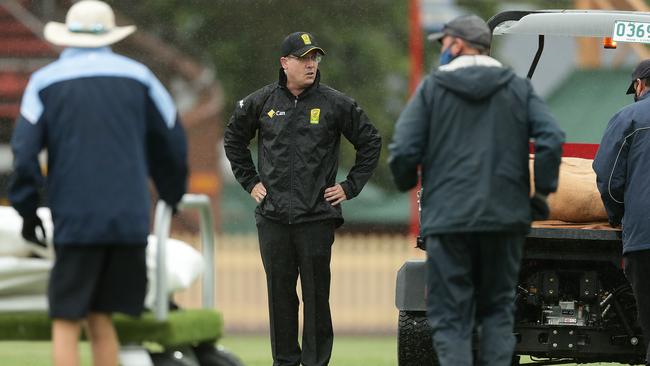 Umpires consider their options during a rain delay in the Thunder-Stars match.