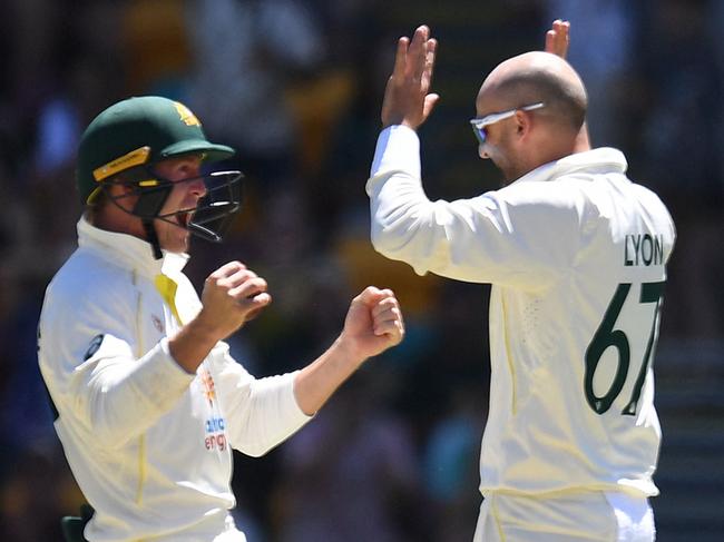 Nathan Lyon of Australia (R) celebrates with teammate Marnus Labuschagne after taking the wicket of EnglandÃs David Malan, his 400th career Test wicket, during day four of the first Ashes cricket Test match between England and Australia at the Gabba in Brisbane on December 11, 2021. (Photo by Dan PELED / AFP) / -- IMAGE RESTRICTED TO EDITORIAL USE - STRICTLY NO COMMERCIAL USE --