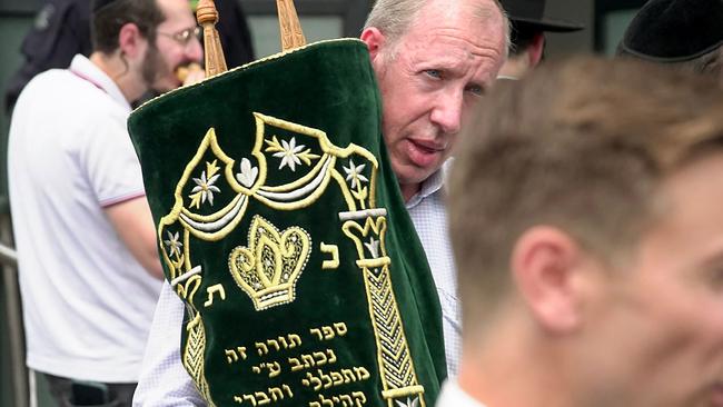 Jewish community members remove holy scrolls from the burnt Adass Israel Synagogue. Picture: Tania LEE / AFP