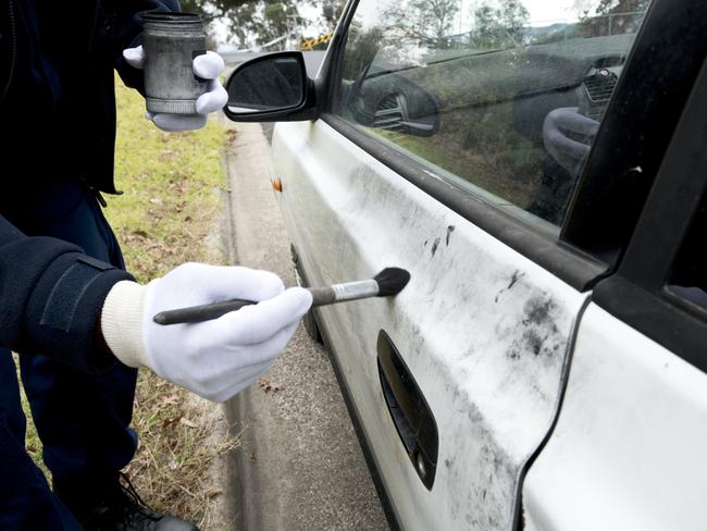 Police dust a car for evidence after a carjacking.