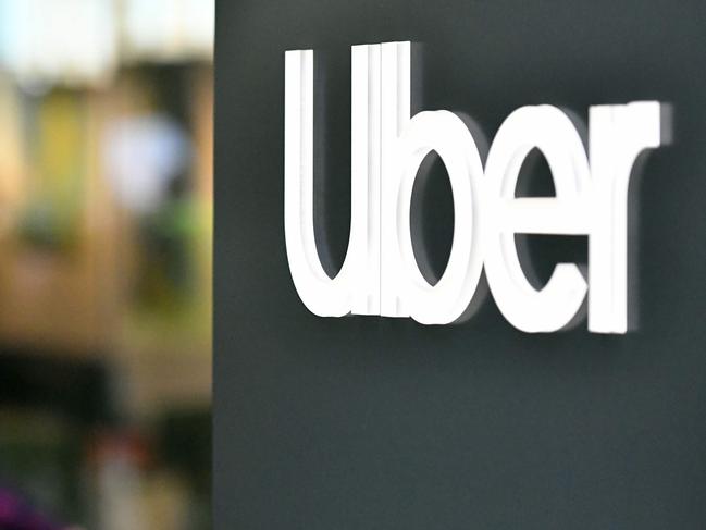 (FILES) In this file photo an Uber logo is seen on a sign outside the company's headquarters location as people protest nearby in San Francisco, California on May 8, 2019. - Uber on May 18, 2020 announced it is cutting a quarter of its global workforce and trimming investment to survive the financial hit to its business from the coronavirus pandemic. The San Francisco-based company is laying off about 3,000 people and stopping some investments unrelated to its core ride-share and delivery businesses, according to chief executive Dara Khosrowshahi. (Photo by Josh Edelson / AFP)