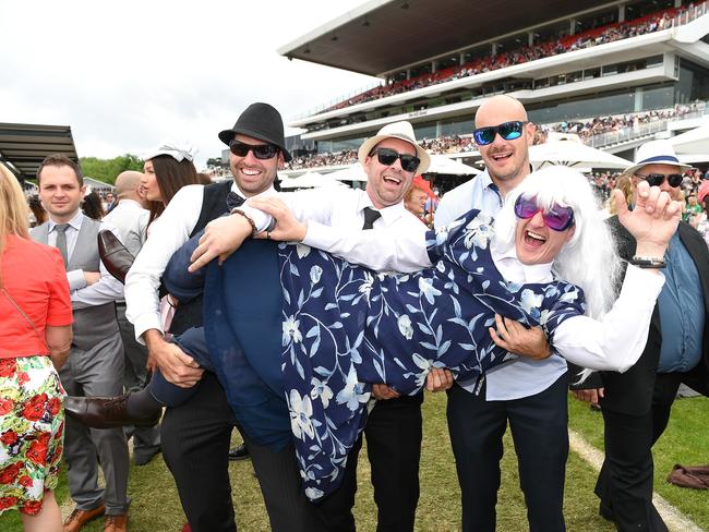 Best men Tyler Gibson, James Shannon, Michael Snelson hold up buck Joel Pearce at the 2014 Melbourne Cup. Picture: Jake Nowakowski