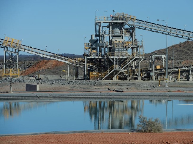 A water reserve pond sits in front of conveyors at the processing plant of Evolution Mining Ltd.'s gold operations in Mungari, Australia, on Tuesday, Aug. 8, 2017. Evolution Mining is Australia’s second-largest gold producer. Photographer: Carla Gottgens/Bloomberg