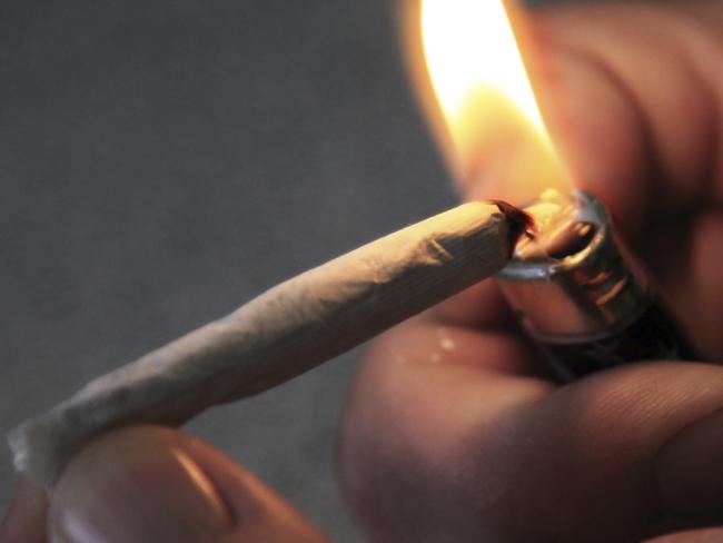 A man lights what is presumably a Marijuana cigarette in a dark environment. Better known as pot or a joint, this drug goes by many names. In actuality this is a hand-rolled tobacco cigarette, no actual drugs were used in this photo. Shot using ambient light from the lighter. Shallow depth of field, focus is on tip of cigarette and flame. Canon 5D Mark II, 24-105L lens.