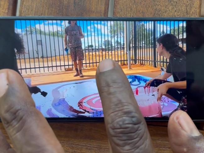 Stills taken from video where a non-indigenous employee is seen contributing to a painting by (Indigenous) artist Yaritji Young. The employee wearing darker clothing and holding a paint brush is Rosie Palmer, manager of Tjala Art in the settlement of Amata in the APY Lands.