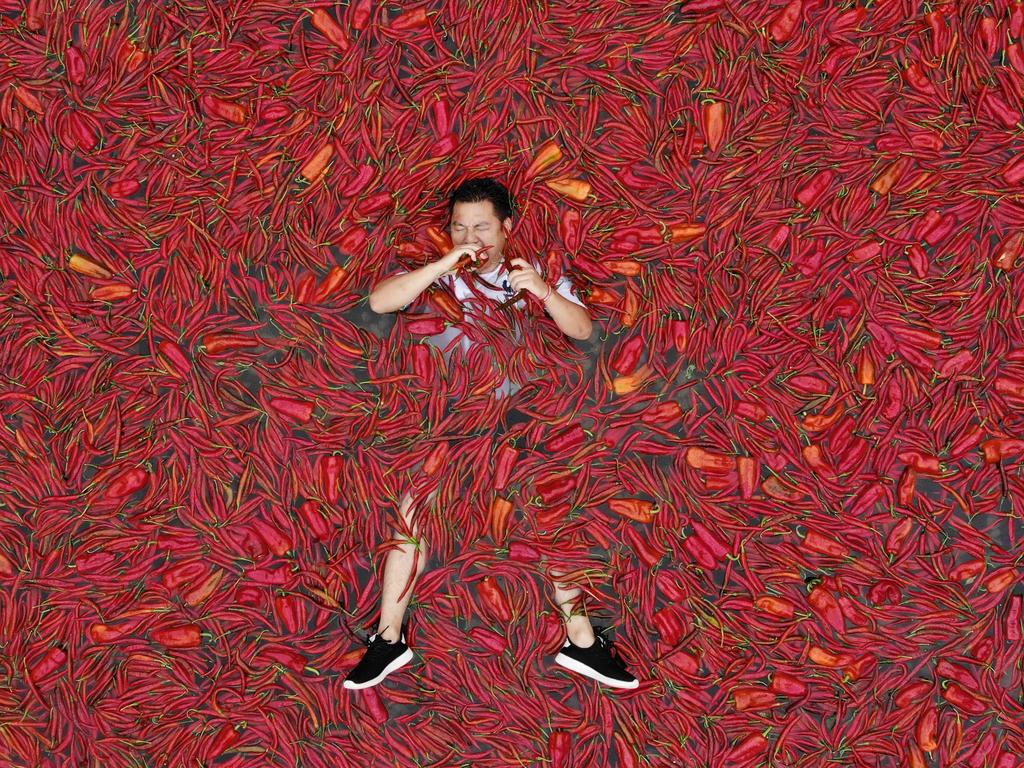 A contestant lays in a chilli-covered pool to eat the hot peppers during a chilli-eating contest in Ningxiang, China. Tang Shuaihui ate 50 chillies in one minute to win. Picture: Visual China Group via Getty Images