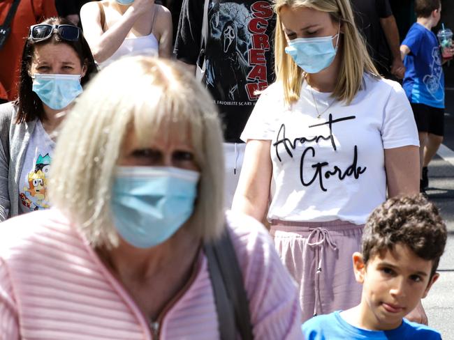 MELBOURNE, AUSTRALIA - DECEMBER 22: People wearing face masks cross Collins Street on December 22, 2021 in Melbourne, Australia. Victoria's COVID-19 case numbers are on the increase across the state, with health authorities also reporting new cases of the Omicron variant. (Photo by Diego Fedele/Getty Images)