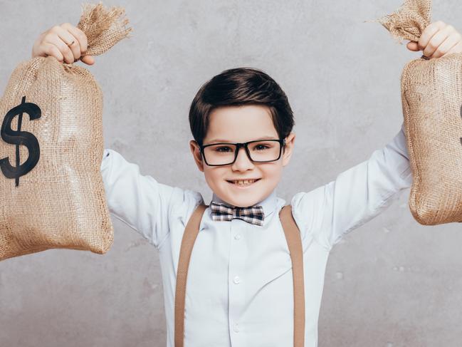 portrait of little boy in eyeglasses holding moneybags isolated on grey; children money investing generic