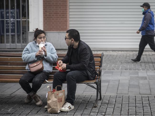 Two residents eat McDonalds on a bench in Hubei Province, China. Picture: Getty