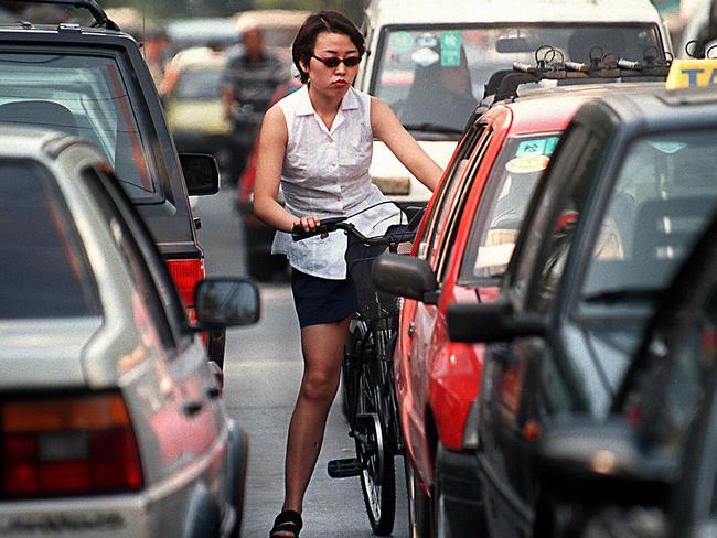 A cyclist makes her way through a busy street in Beijing.