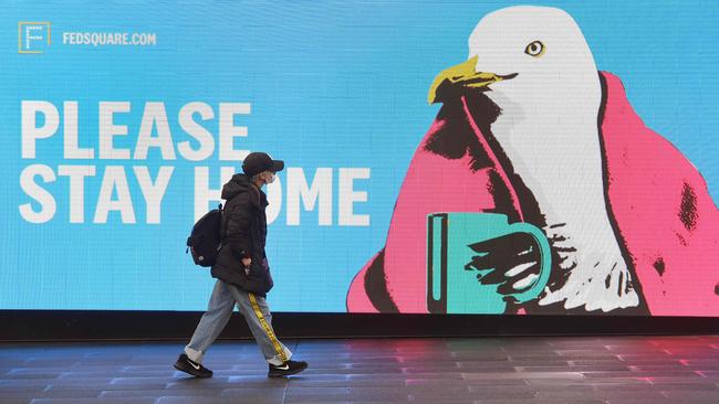 A woman walks past a sign urging people to stay home in Melbourne on Friday as the city battles its outbreak of the COVID-19 coronavirus. Picture: AFP