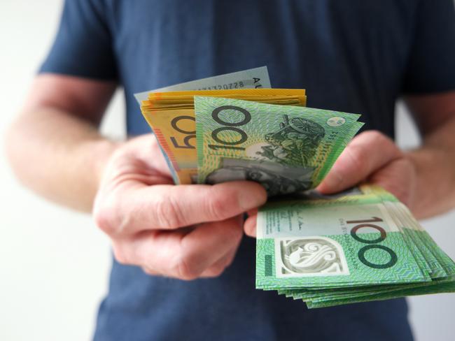 A man counting Australian dollar bills. A picture that describes buying, paying, handing out money, or showing money. Australian cash money generic