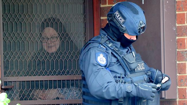 A woman and child look on as police conduct a doorknock in the neighbourhood. Picture: Alex Coppel