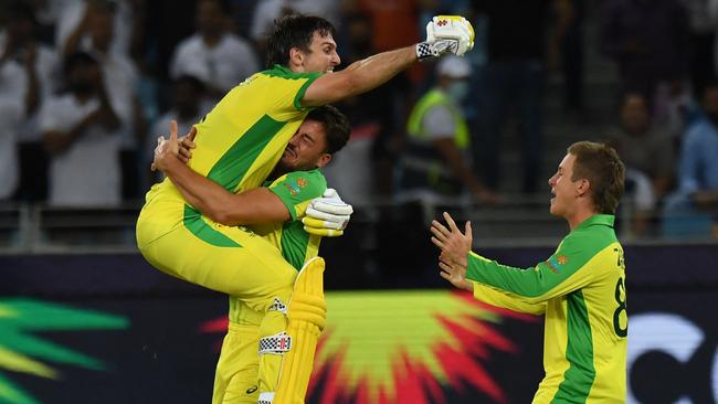 Player of the final Mitchell Marsh, left, celebrates the win with Marcus Stoinis and Adam Zampa, right. Picture: AFP