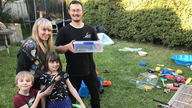 The Snake Hunter Mark Pelley with the snake in a plastic container. Ashley, 4 and Ruby, 8 are with mum Adie Tudor.