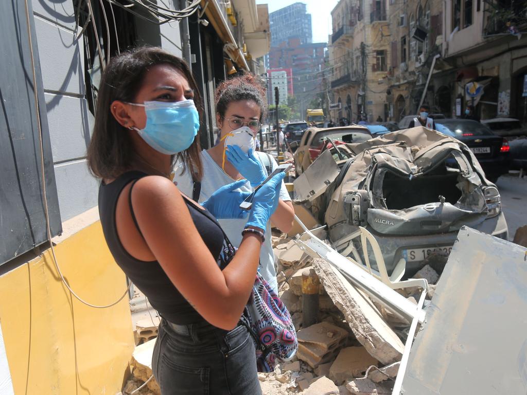 Young Lebanese women wearing protective masks and gloves against the coronavirus pandemic survey the rubble in Beirut's Gimmayzeh commercial district. Picture: STR / AFP