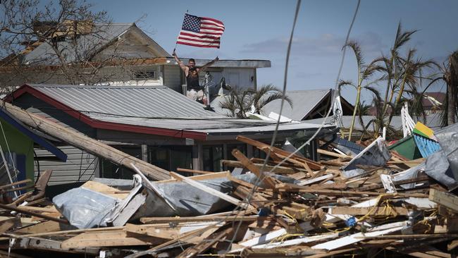 Whitney Hall waves to a friend from the remains of his home while waving the American flag amid wreckage left in the wake of Hurricane Ian on the island of Matlacha. Picture: AFP