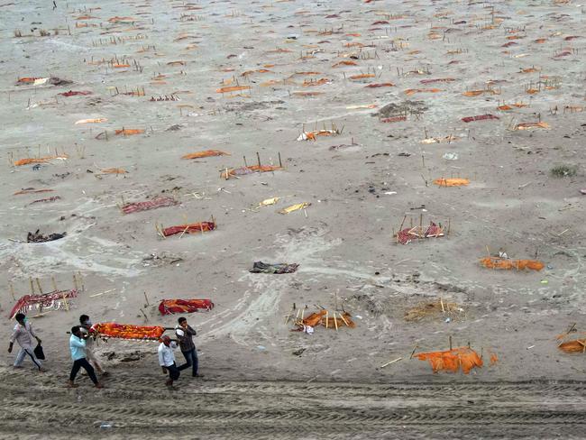 Relatives carry a body for cremation past the graves of people on the banks of the Ganges River in Shringverpur, northwest of Allahabad, Uttar Pradesh, India. Picture: Getty Images