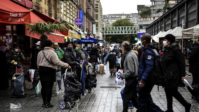 People wearing face masks pull trolleys as they shop beside the main market (R) in the popular city of Saint-Denis, a northern Paris suburb . Picture: AFP