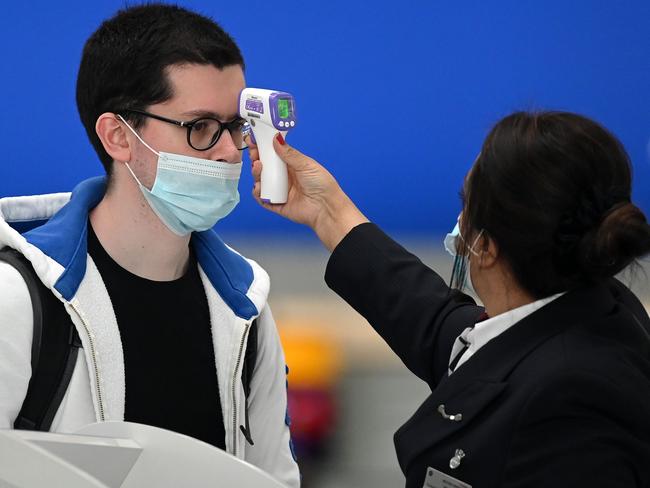 (FILES) In this file photo taken on July 10, 2020 Passengers wearing face masks or covering due to the COVID-19 pandemic, have their temperature taken as they queue at a British Airways check-in desk at Heathrow airport, west London. - London's Heathrow airport on July 29, 2020, urged the government to create a coronavirus testing programme for travellers to replace quarantines, as it announced more than a billion pounds in losses in 2020. The air hub, usually the busiest in Europe, said it had recorded a pre-tax loss of Â£1.1 billion ($1.4 billion, 1.2 billion euros) in the first six months of the year, as the pandemic decimates the aviation sector. (Photo by DANIEL LEAL-OLIVAS / AFP)