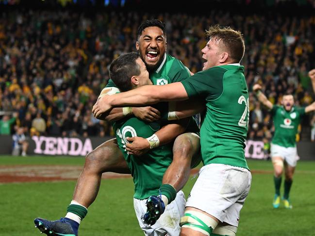 Ireland's Bundee Aki (centre) jumps on teammate Johnny Sexton (left) with Jordi Murphy as they celebrate winning the Third Test rugby match between Australia and Ireland at the Allianz Stadium in Sydney, Saturday, June 23, 2018. (AAP Image/David Moir) NO ARCHIVING, EDITORIAL USE ONLY