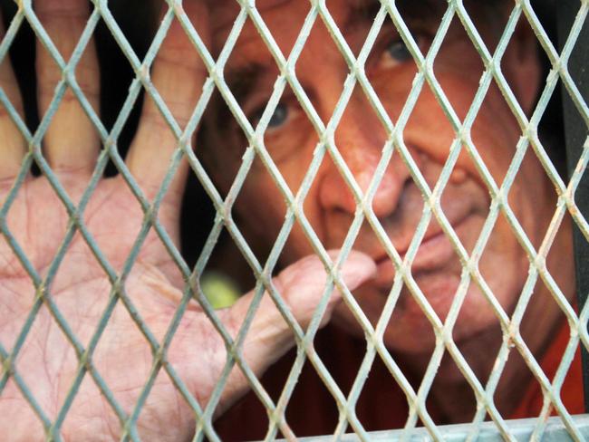 Australian filmmaker James Ricketson gestures from inside a prison truck upon his arrival at Phnom Penh Municipal Court in Phnom Penh, Cambodia, Friday, June 15, 2018. The court on Friday delayed its hearing on Ricketson who has been held in prison since being charged with spying for an unspecified foreign country, after flying a drone at a political rally in June 2017. (AP Photo/Heng Sinith)