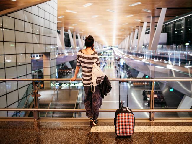 Image of a young woman with a suitcase traveling solo. Taken in the evening at the Qatar airport in Doha.