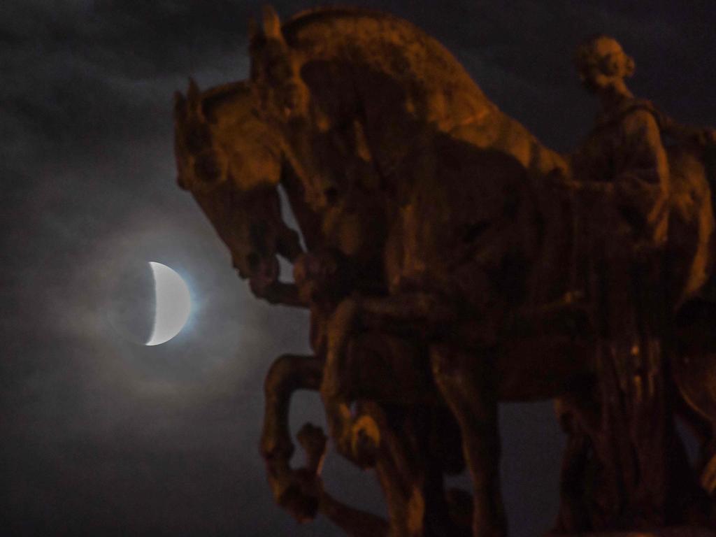 The moon is seen behind the Independence Monument during a partial lunar eclipse in Sao Paulo, Brazil, on July 16, 2019. (Photo by NELSON ALMEIDA / AFP)