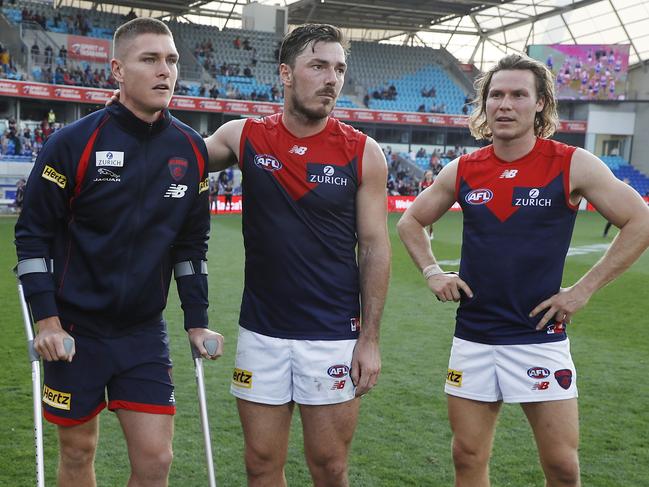 HOBART, AUSTRALIA - MAY 02: Adam Tomlinson of the Demons is seen injured with teammates Trent Rivers of the Demons, Michael Hibberd of the Demons and Ed Langdon of the Demons during the 2021 AFL Round 07 match between the North Melbourne Kangaroos and the Melbourne Demons at Blundstone Arena on May 02, 2021 in Hobart, Australia. (Photo by Dylan Burns/AFL Photos via Getty Images)