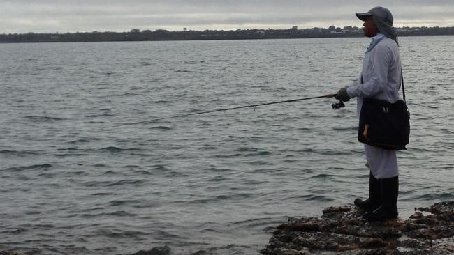 Land-based fishing legend Hiro Nakamura works a lure across a shallow rocky point for barra early in the morning