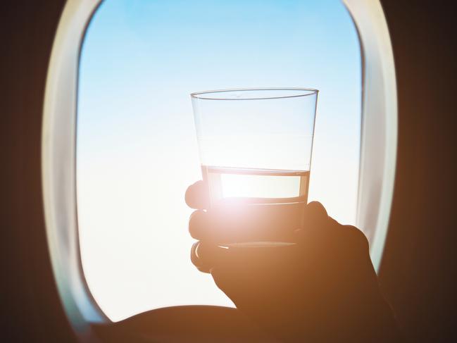 ESCAPE:  Comfortable traveling by airplane. Passenger is holding glass of the wine during the flight.  Picture: Istock