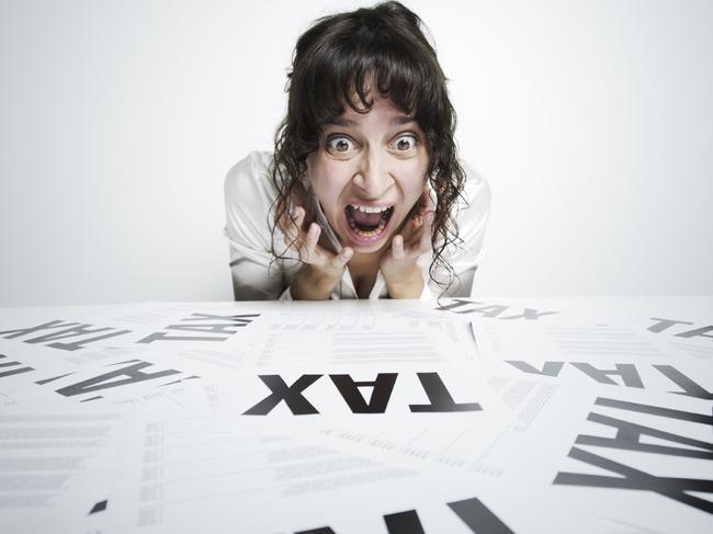 Astonished woman looking at a bunch of worrying tax forms on her desk