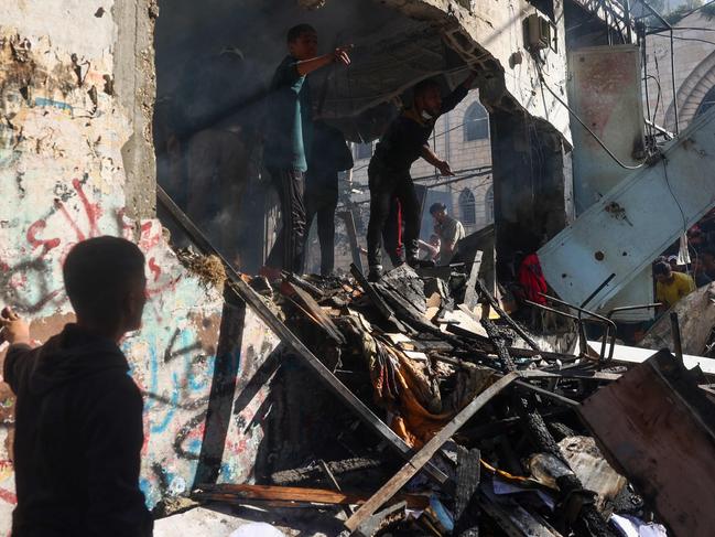 Palestinians check the destroyed Maghazi Camp Services Club building following an Israeli strike on the Maghazi refugee camp in the Gaza Strip on October 24, 2024, amid the ongoing war between Israel and Hamas.  (Photo by Eyad BABA / AFP)