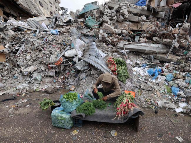 A young Palestinian man sells vegetables in front of a building destroyed in Israeli strikes in Rafah in the southern Gaza Strip. Picture: AFP