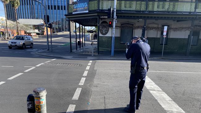 A Crime Scene Investigation Unit officer taking pictures of the intersection where a young man was seriously injured in a fight on Saturday morning. Picture: Kathryn Birmingham