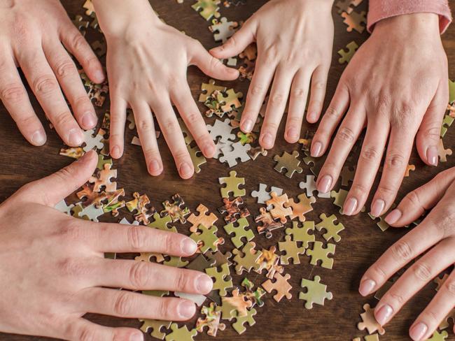 Close-up partial view of family with one child playing with puzzles on table