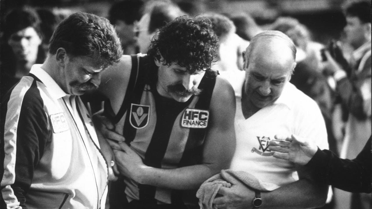 30 Sept 1989. Hawthorn footballer Robert DiPierdomenico after puncturing a lung during the Grand Final - sport action afl injury injure.Robert DiPierdomenico is helped from the field by trainer Bob Holland (R) after puncturing a lung. 1989 Grand Final. Hawthorn v Geelong. MCG.d