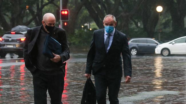 Chris Dawson (right) and his brother Peter Dawson battle Sydney’s bad wet weather on their way to the Supreme Court on Tuesday. Picture: Gaye Gerard