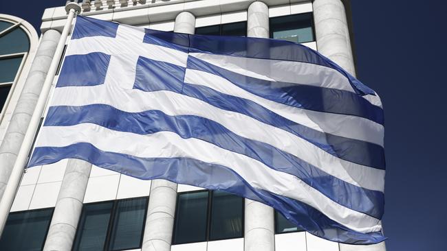 FILE - In this Feb. 3, 2015, file photo, a Greek flag flies outside the Athens Stock Exchange. In 2012, financial markets were rattled by the possibility Greece would elect a left-wing government, default on their debts and drop the euro currency. In 2015, the left-wing party, Syriza, holds power in Athens. Greece actually did miss a loan payment to the International Monetary Fund late Tuesday, June 30, 2015. And the nation's future in the eurozone hinges precariously on a referendum Sunday, July 5, 2015. (AP Photo/Petros Giannakouris, File)