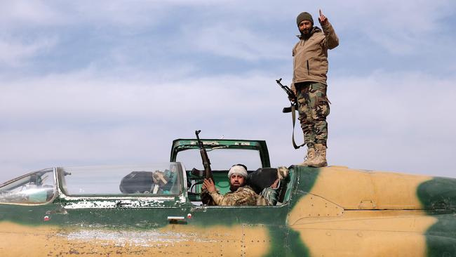 Syrian opposition fighters standing on a captured Syrian Air Force plane at a military airport. Picture: AFP