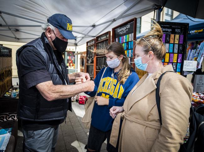 Brian Marriott serves Emily Ward and Bec Ward, from Brisbane, at his Celtmania jewellery stall at Salamanca Market. Picture: Richard Jupe