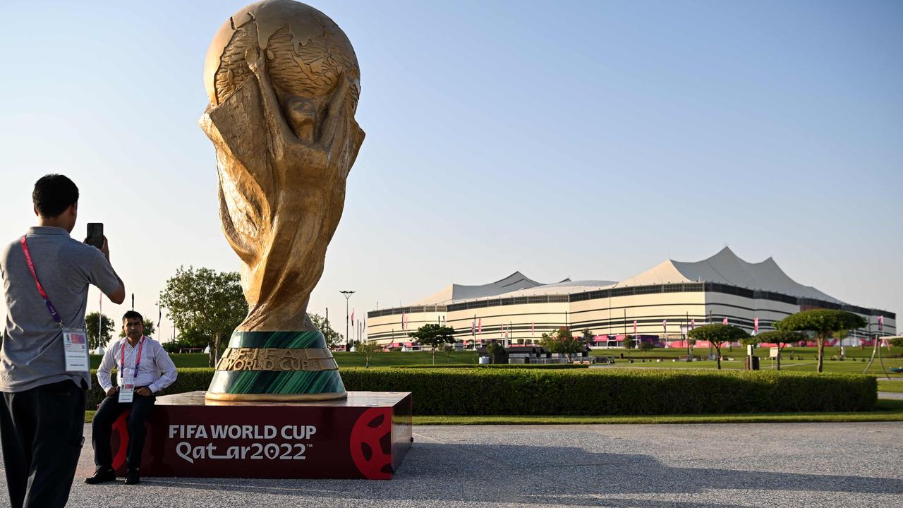 A man takes a picture of a FIFA World Cup trophy replica.