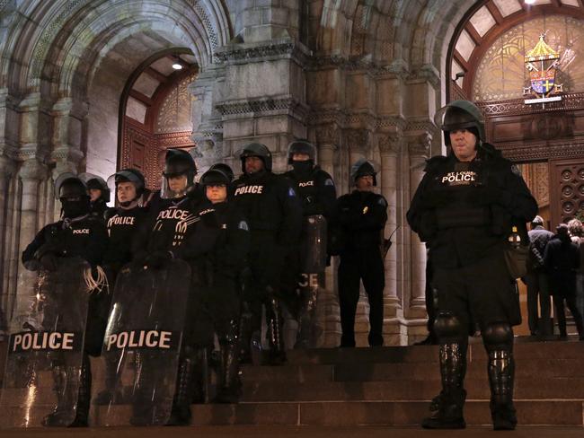 Merry Christmas ... Heavily armed St. Louis Police officers guard the entrance to the Cathedral Basilica before Midnight Mass as protesters held a candlelight vigil. AP
