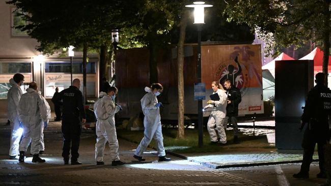 Forensic police wearing white coverall suits as they search for evidence. Picture: AFP.