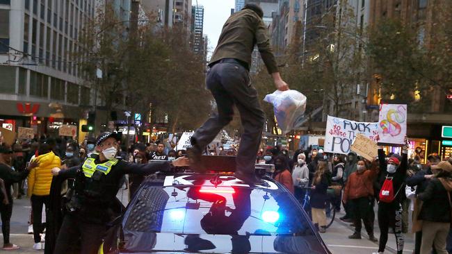 .A protester runs across a Police car during Saturday’s rally. Picture: Wayne Ludbey