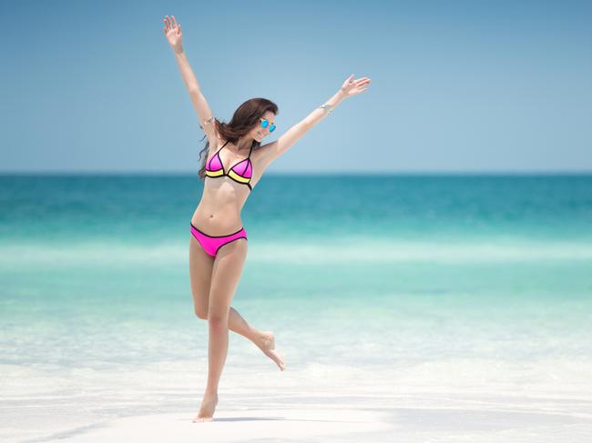 Beautiful woman enjoying her holidays in a colorful bikini on a white sand in the middle of a turquoise tropical ocean. Nikon D810. Converted from RAW.