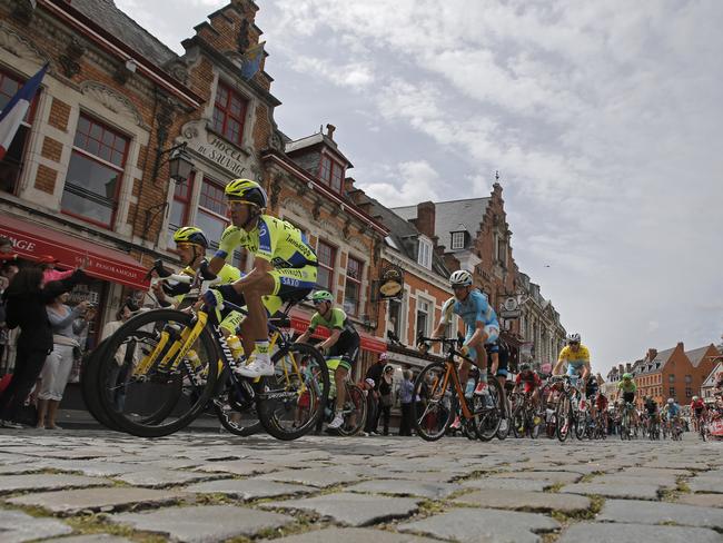 The pack with Spain's Alberto Contador, front left, and Italy's Vincenzo Nibali, wearing the overall leader's yellow jersey, rear right, passes over cobblestones in Cassel, during the fourth stage.