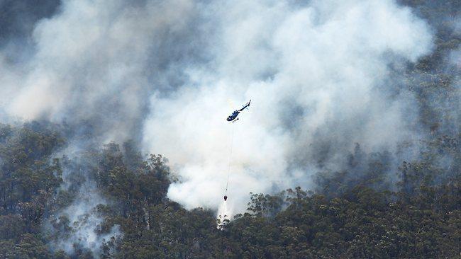 A helicopter tackles a blaze near Ulladulla. Pilot David Black died yesterday while helping battle the same blaze. Picture: Anthony Reginato