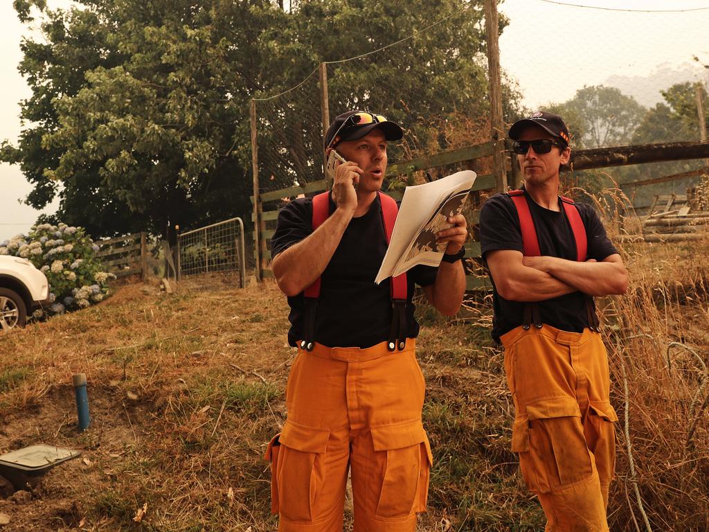 Tasmania Fire Service personnel including Justin Park, left, looks for a spot fire at Crowthers Road, Castle Forbes Bay. Picture: LUKE BOWDEN