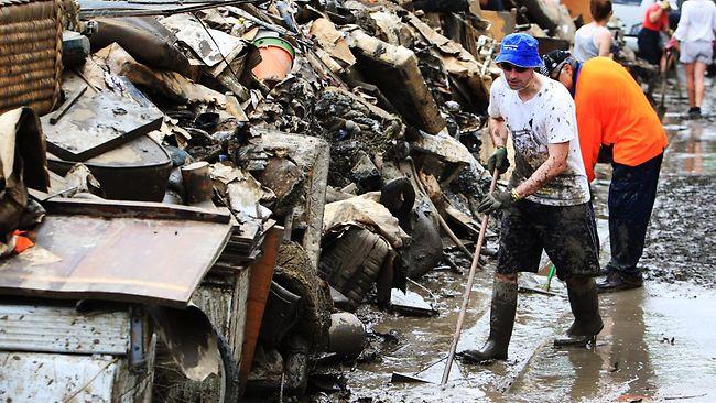 Volunteers remove mud and rubbish from St Lucia in Brisbane yesterday. Picture: Craig Greenhill